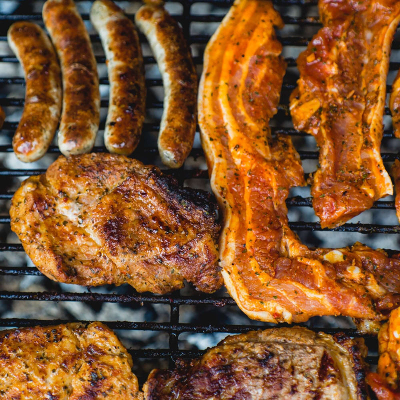 Selection of meats on a grill with BBQ rub on them.